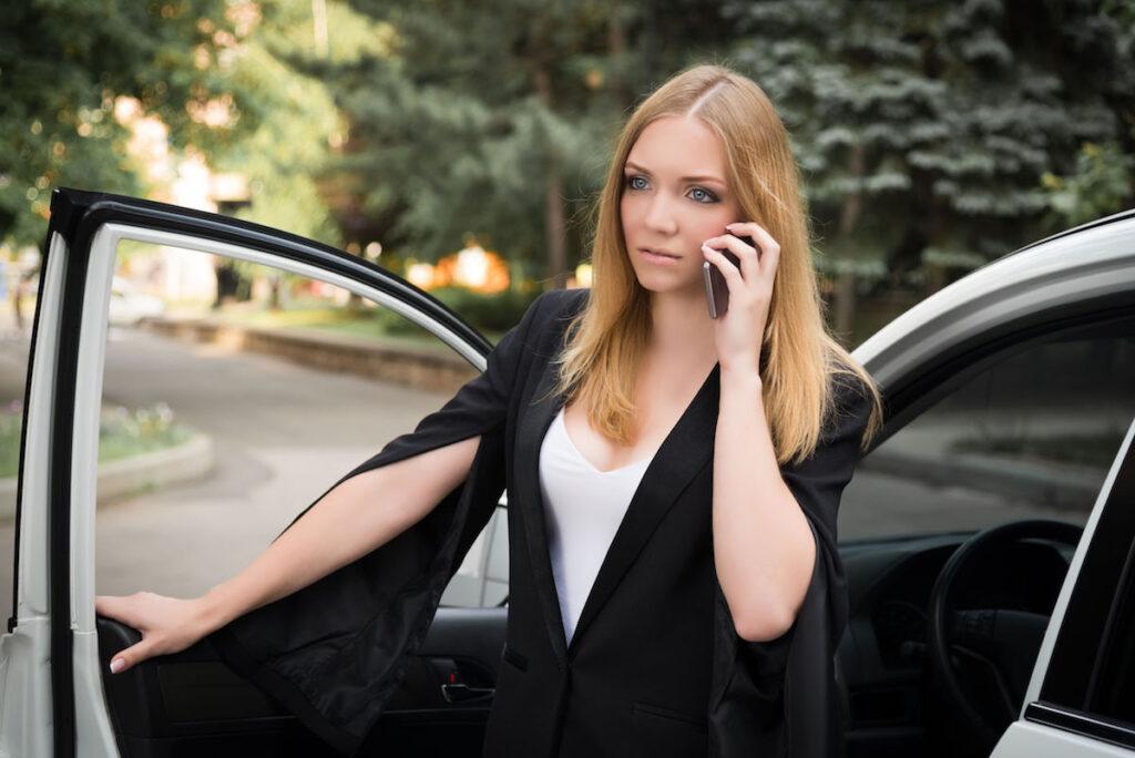 女孩正在車附近打電話。