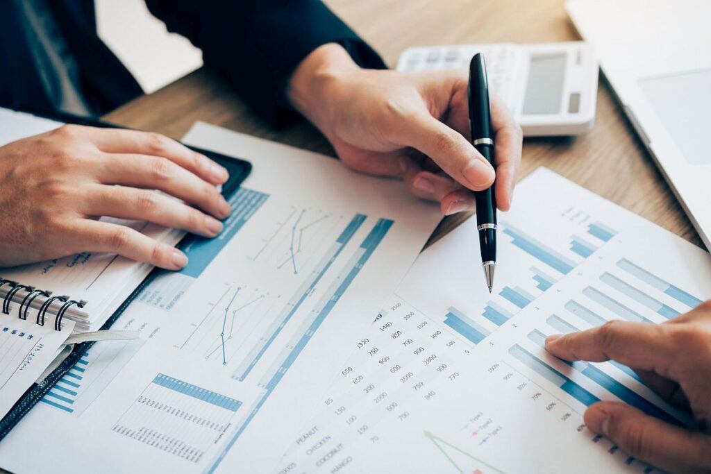 The accounting staff of the company are jointly analyzing the graph of the expenses on the desk in the office.