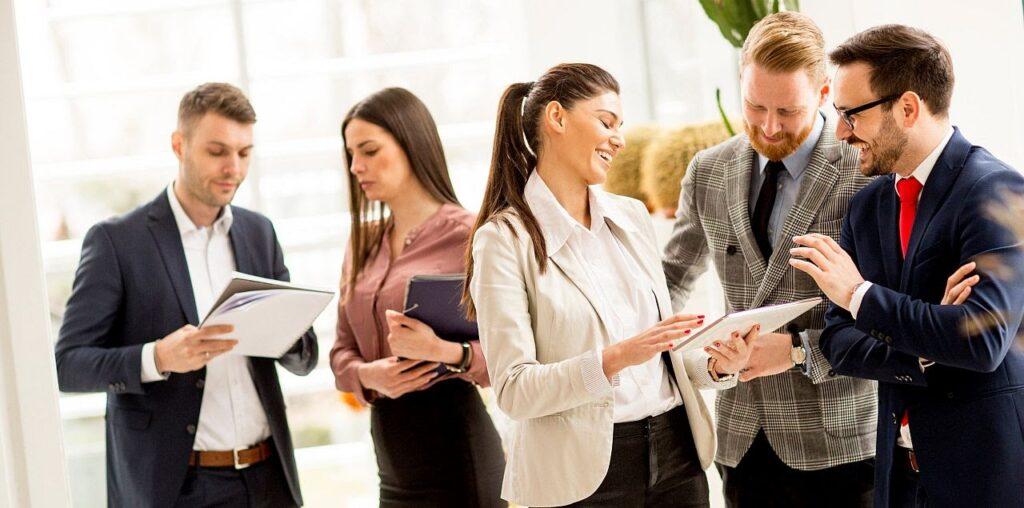 Meeting of group of businesspeople in the office standing in front of large window in modern office