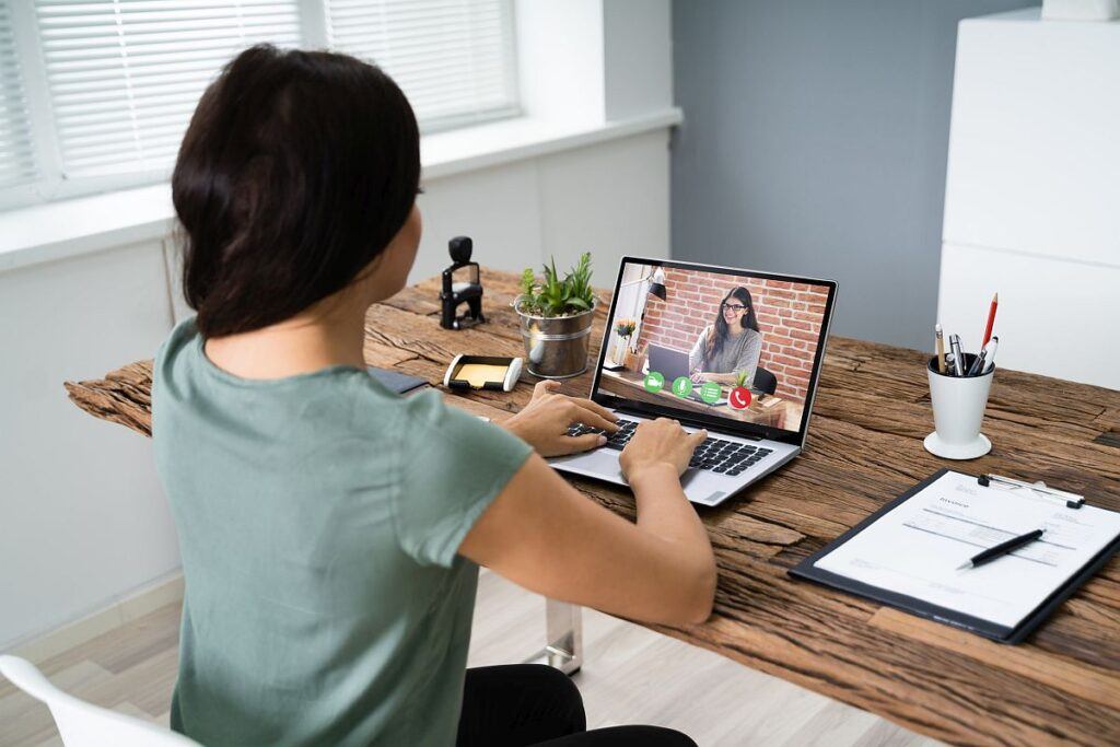 Young Woman Videoconferencing With Colleague On Computer At Desk