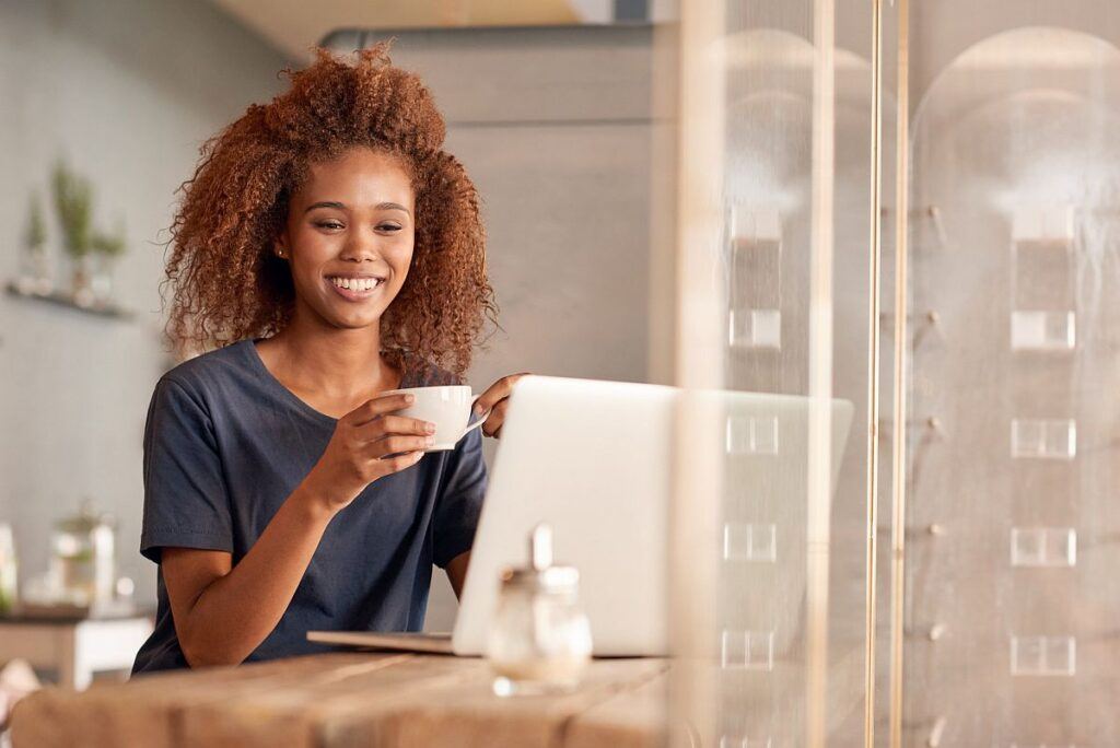 ラップトップで作業し、コーヒーを飲む若い女性